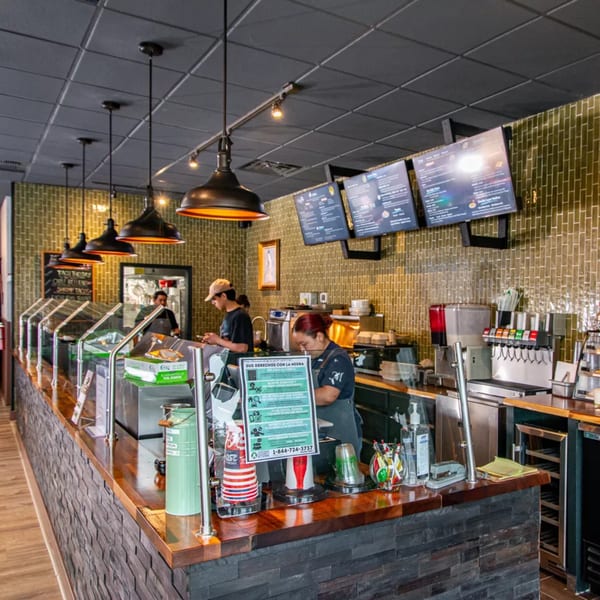 Interior of Miguelito's Cocina Mexicana, showing a counter with food warmers, staff, and menu screens.
