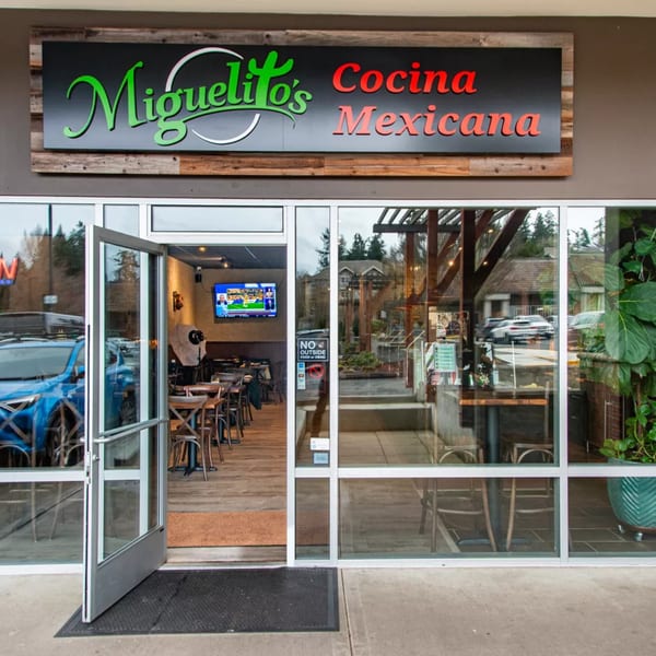Exterior view of Miguelito's Cocina Mexicana entrance with open door and visible interior dining area.