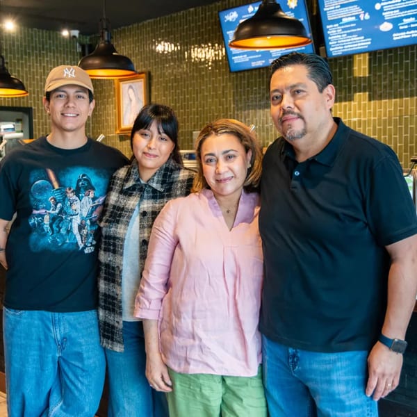Four smiling people, two men and two women, stand together in Miguelito's Cocina Mexicana.