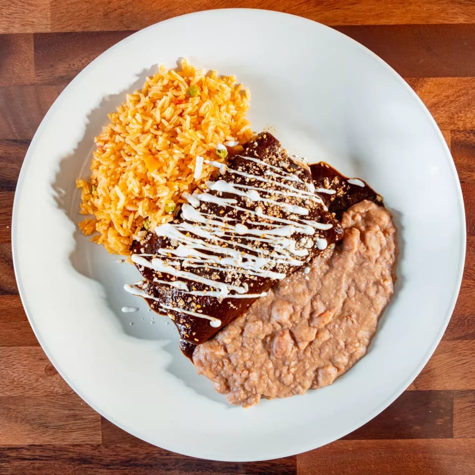 Miguelito's Cocina Mexicana's chicken mole with rice and refried beans on a white plate.