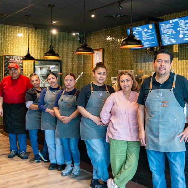 Miguelito's Cocina Mexicana staff, seven people in aprons, standing in a line inside the restaurant.