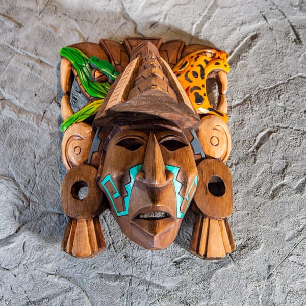 Intricately carved wooden Mexican mask with turquoise accents, a green snake, and a spotted jaguar.