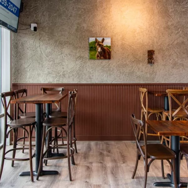 Interior of Miguelito's Cocina Mexicana with high-top tables, wooden chairs, and a donkey painting on the wall.
