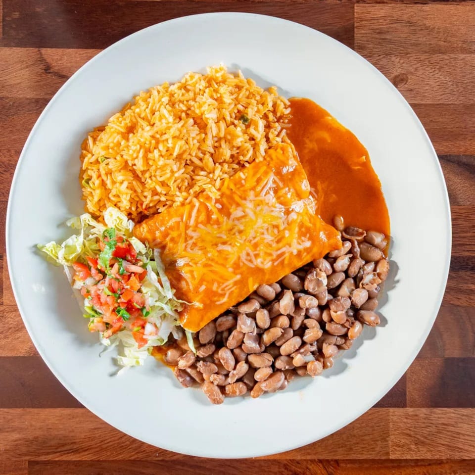 Miguelito's Cocina Mexicana enchilada plate with rice, beans, and a side salad on a white plate.