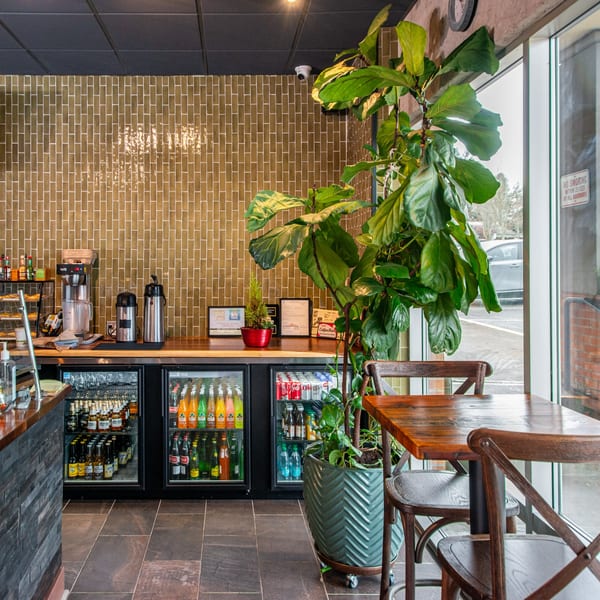 Interior of Miguelito's Cocina Mexicana with a beverage bar, potted plant, and wooden tables.