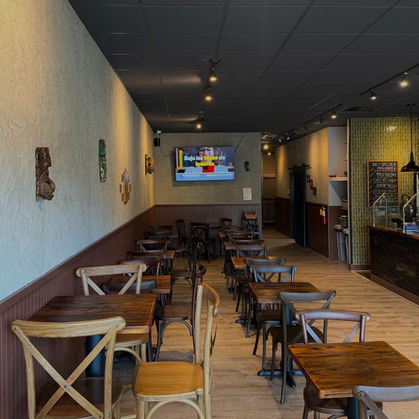 Interior of Miguelito's Cocina Mexicana with rows of wooden tables and chairs, and a specials board.